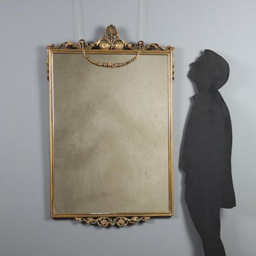 Carved and gilded mirror. Frame embellished with Neoclassical carvings on the top, leaves and flowers on the base. Some...