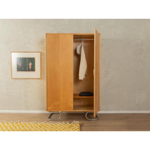 A classic wardrobe from the 1960s. The body is made of cherry veneer with two doors, one shelf, a clothes rail, and new...