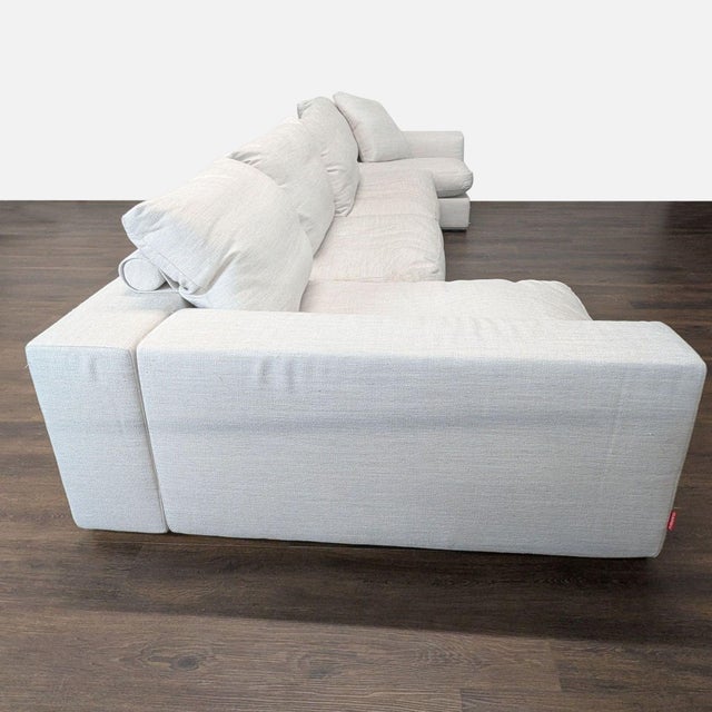 This Flexform sectional sofa offers a spacious and modern seating option in a light ivory fabric. Features deep cushions,...