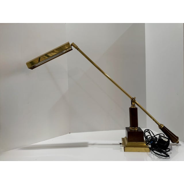 Vintage House of Troy counterbalance piano or desk lamp featuring polished brass-tone metal with dark wood accents. The...