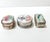 This set of three vintage trinket boxes combines delicate hand-painted porcelain with detailed silverplate casings, each...