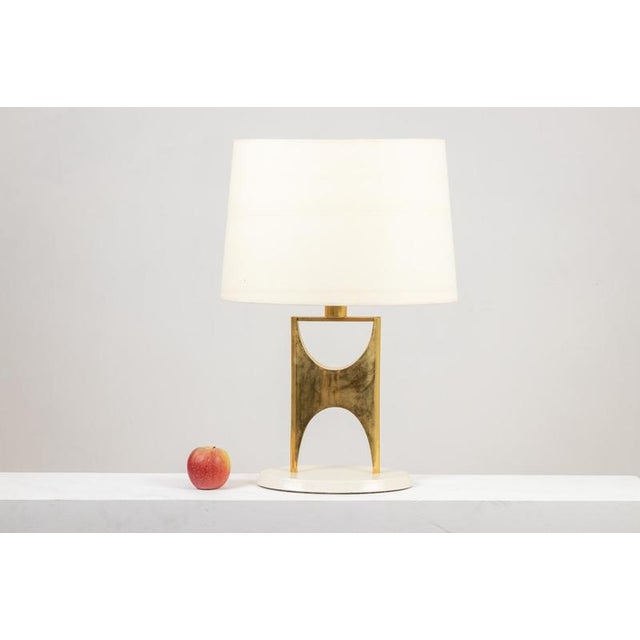 Geometric gilded bronze lamp in the shape of an H. Work made in the 20th century. Sand white colored base. Decoration....