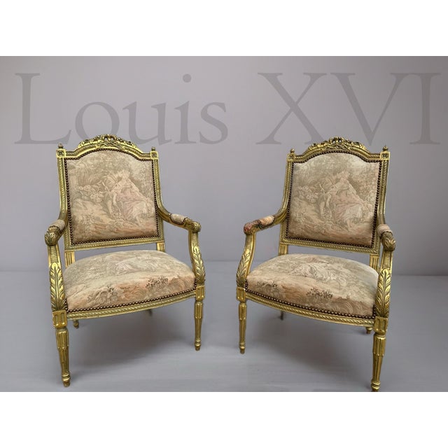Elegant pair of late 20th century Louis XVI–style armchairs featuring finely carved giltwood frames with refined...