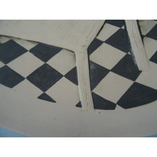 The black and white drawing on the plate showcases a stylized representation of everyday objects. The artist's use of...