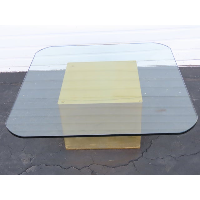 This Coffee Table is made out of metal, and glass. This Table has Mid Century style and design, square metal base, brass...