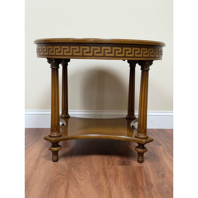 Vintage Regency / Neoclassical style round side table in a light-toned wood finish, detailed with a Greek key frieze at...
