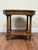 Vintage Regency / Neoclassical style round side table in a light-toned wood finish, detailed with a Greek key frieze at...