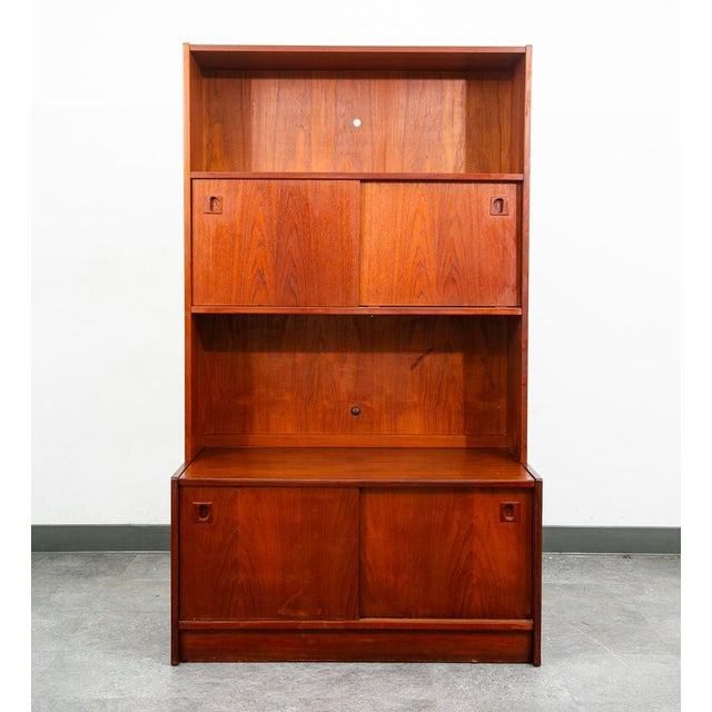 Functional bookshelf in teak. Bottom section offers sliding doors with solid teak handles. The above bookshelf storage...