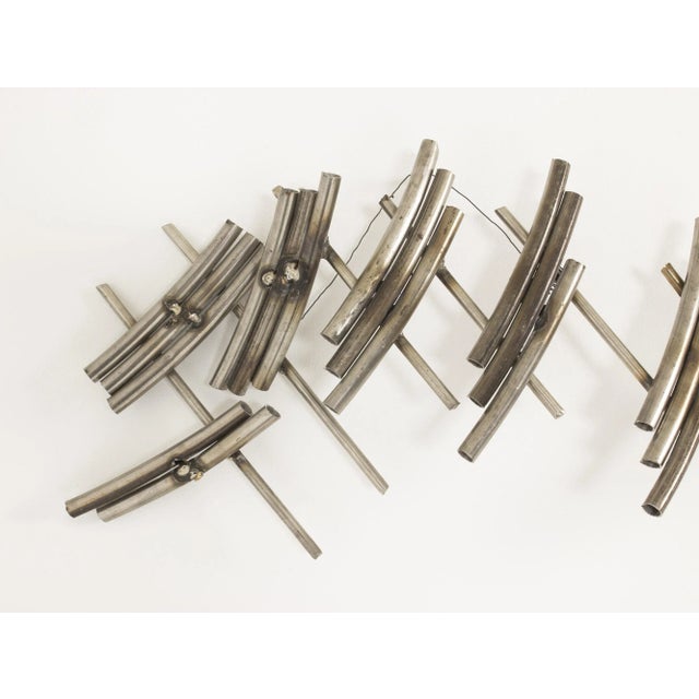 Striking steel wall sculpture by Fred Leyman, with movement and a musical quality in its shape. Hangs from a steel thread....