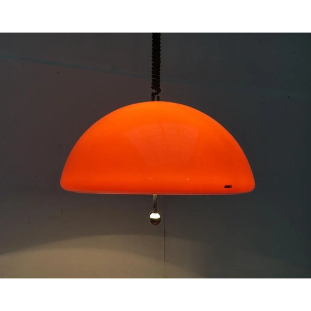 Rare train pendant lamp of Harvey Guzzini. The large plastic screen is executed in orange. On the inside of the screen is...