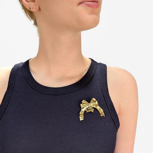 A fine Mexican vermeil figural brooch. By William Spratling. In gilt sterling silver. In the form of a ribbon bow with...