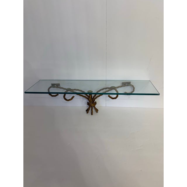 This vintage Hollywood Regency style wall shelf features a twisted gold metal base designed to resemble a braided rope. It...