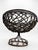 Decorative vintage pedestal basket featuring an openwork metal frame with loosely woven vine- or rattan-like strands...