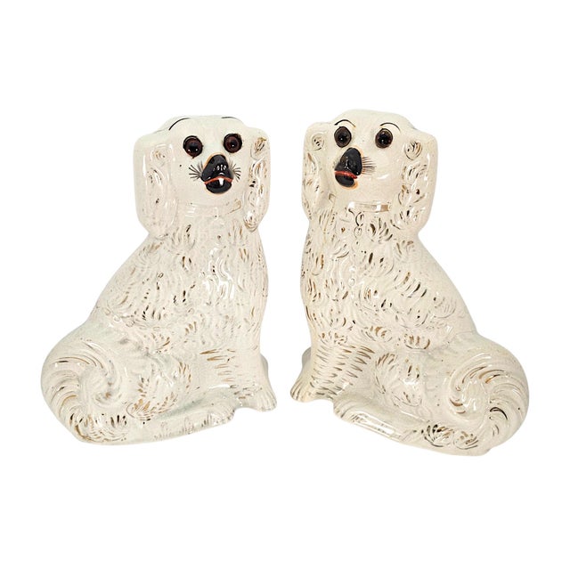 A matched pair of late-Victorian Staffordshire spaniel mantel figures, England, circa 1870–1890, modelled as seated dogs...