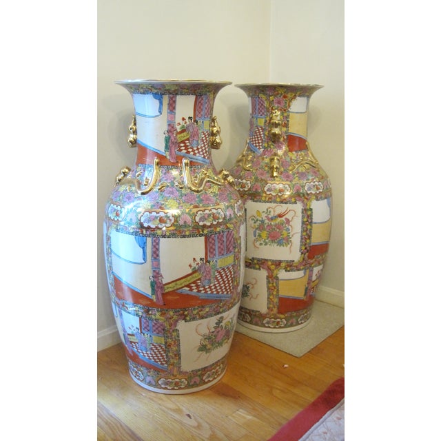 A set of two large Chinese Famille Rose (Canton-style) porcelain floor vases, featuring court scenes, floral panels, and...