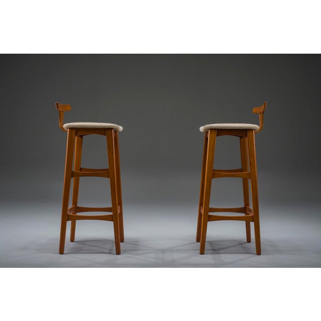 Elegant pair of danish modern bar stools by dyrlund, crafted in solid teak and newly upholstered in premium wool fabric....