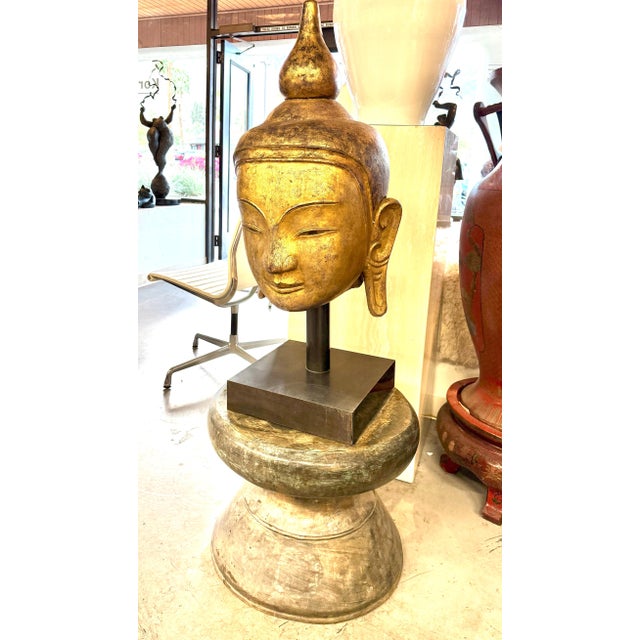 A beautiful Southeast Asian Buddha sculpture. It is gilded carved stone and expertly mounted on a steel rod and base. The...