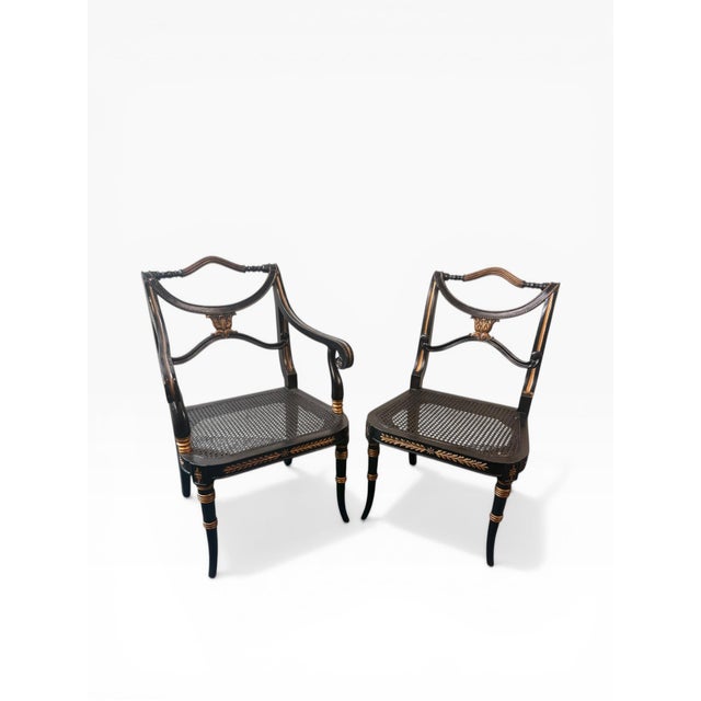 A refined set of four neoclassical Regency-style dining chairs featuring an elegant ebonized finish with warm gilt...