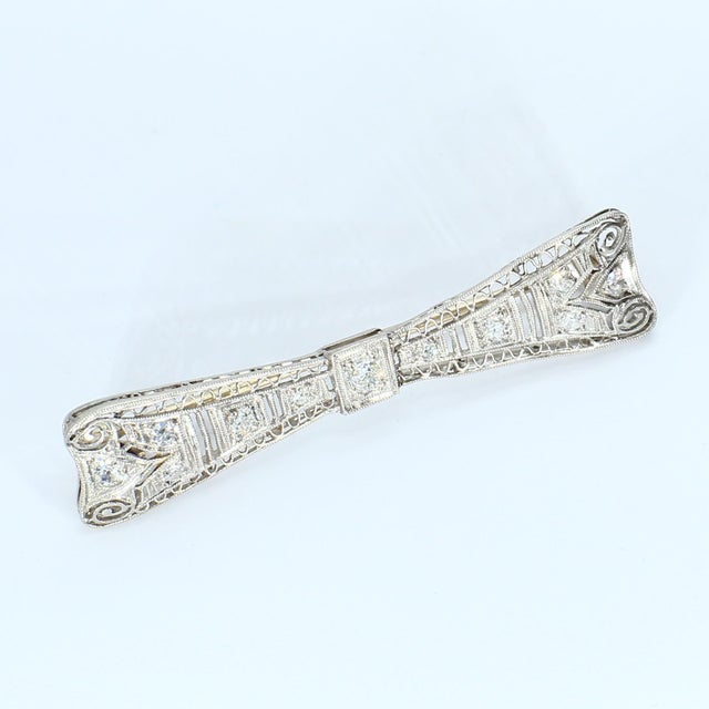 This bow-shaped brooch features intricate detailing with a series of diamonds set throughout its design. Stone Info: Old...
