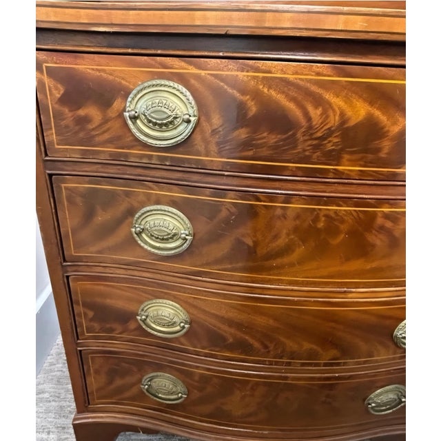 A stunning serpentine-front chest with flame mahogany veneer, bracket feet, and classic batwing brass pulls. This piece...
