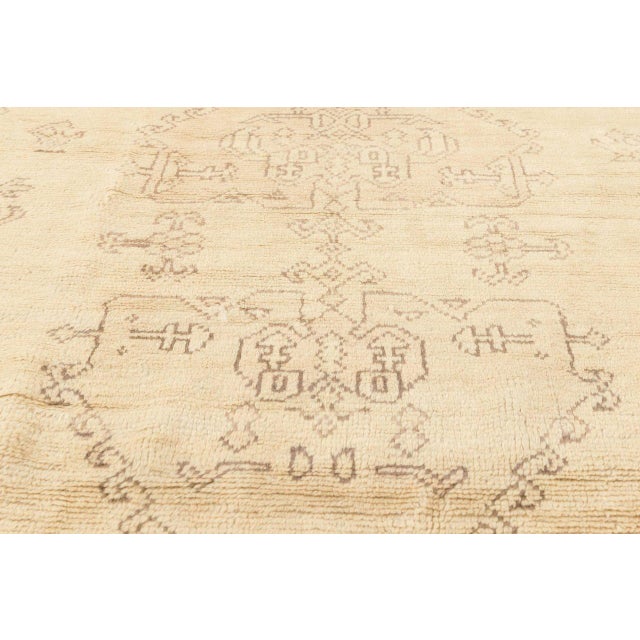 This antique Turkish Oushak rug, dating to the early 1900s, is a masterclass in understated elegance and artisanal...