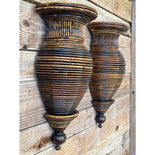 A striking pair of sculptural pencil rattan wall sconces featuring an elongated urn form with deeply ribbed detailing...