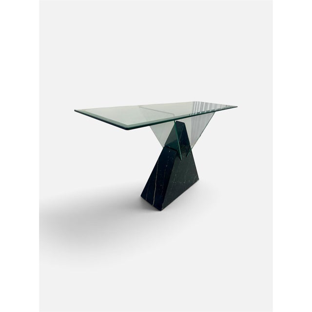 This is a postmodern console table featuring a geometric black marble base and a glass top, often styled similarly to...