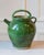 This terracotta jug, produced between the late 19th and early 20th century, is finished in a deep green lead-based glaze...