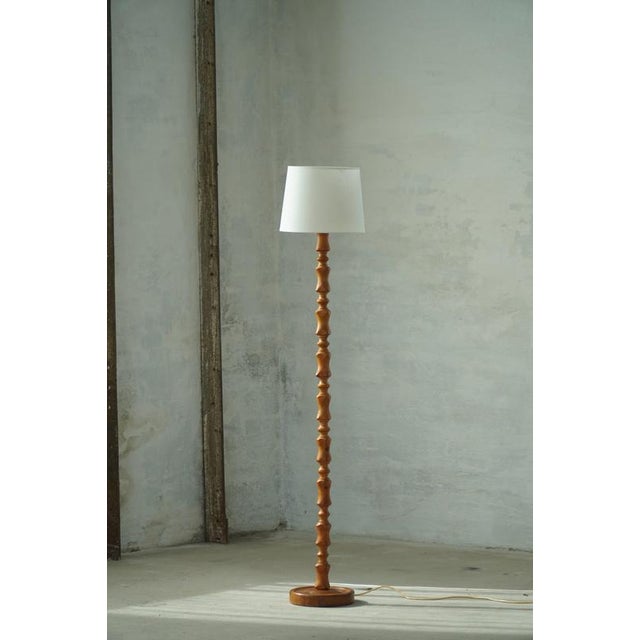 A beautiful and sculptural Scandinavian floor lamp in solid pine, Denmark, circa 1970s. The lamp features a tall, slender...