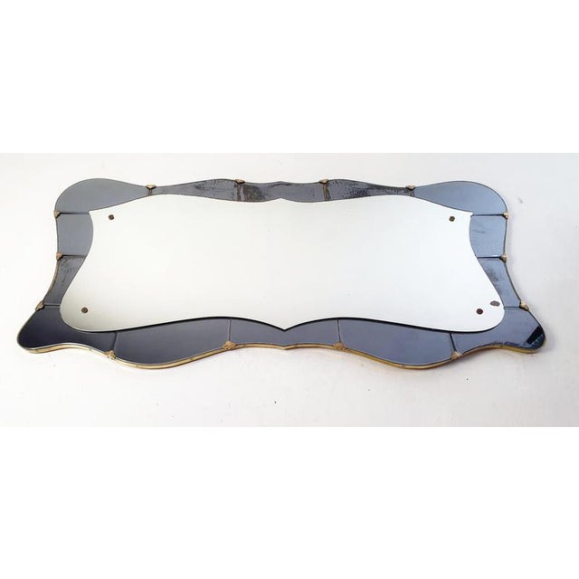 An extaordinary large wall mirror from the 1950's with a butterfly shaped design. The glass by the edges is in dark gray...