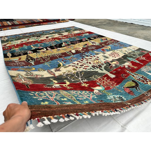 This hand-knotted Afghan pictorial rug is composed of horizontal landscape bands in deep red, teal, gold, and charcoal,...