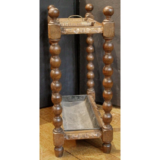 Circa 1880 carved umbrella & stick stand, English. Oak with central brass carrying handle. Bobbin turned, ball tipped...