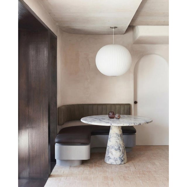 This minimalist table is crafted from viola-veined marble, showcasing a circular tabletop that balances securely and...