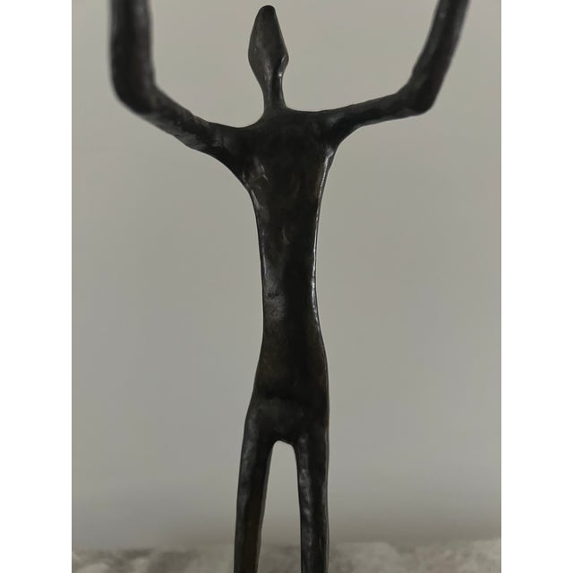 Sculptural modernist figural form in the manner of alberto giacometti, featuring an elongated human figure holding a...