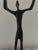Sculptural modernist figural form in the manner of alberto giacometti, featuring an elongated human figure holding a...