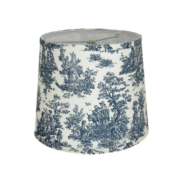 This navy toile drum lamp shade features a classic pastoral design in deep navy tones on a crisp white background,...