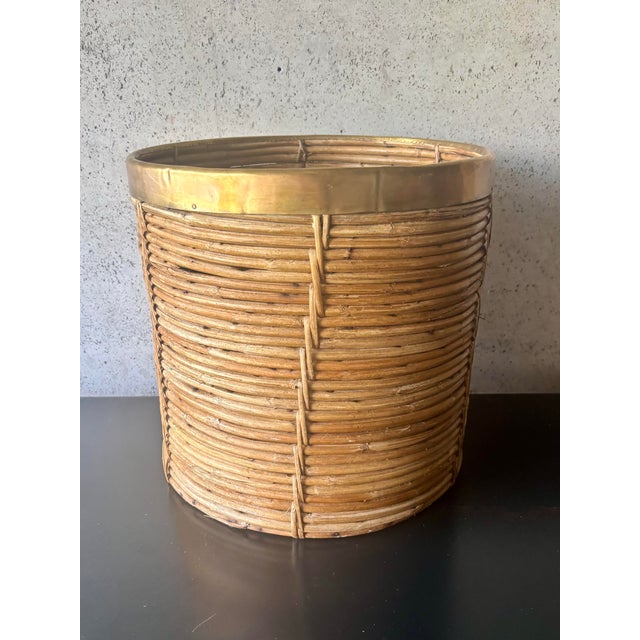 A large vintage pencil reed planter featuring tightly wrapped natural rattan construction accented by a polished brass...