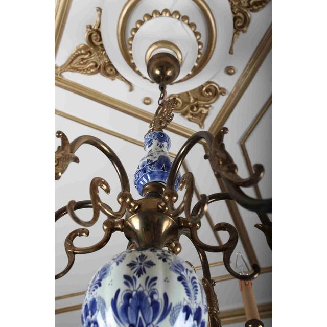 Brass chandelier decorated with hand-painted delft elements. The arms are figuratively decorated with fish. The top part...