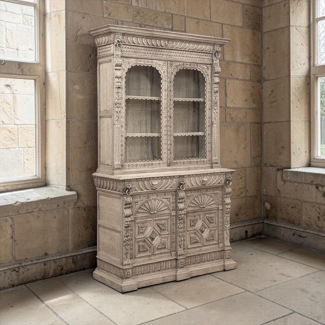 A richly articulated example of Belgian craftsmanship, this tall 19th Century Belgian Hand-Carved Stripped Oak Bookcase...