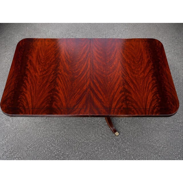 An elegant vintage Regency-style double pedestal dining table showcasing an extraordinary flame mahogany veneer top with...