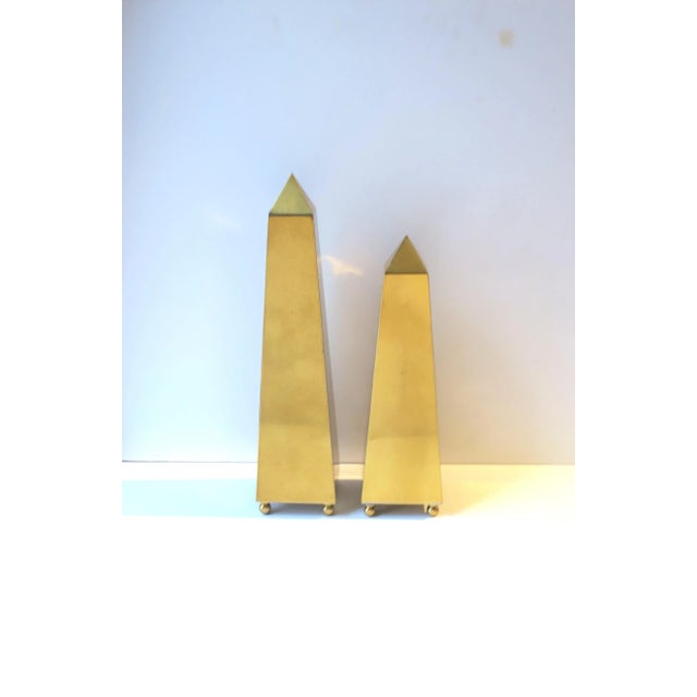 A pair/set of brass Obelisks with ball feet, in the Modern style, circa late 20th century. Pair have a clear lacquer...
