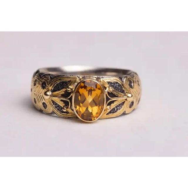 A stunning faceted, oval yellow sapphire ring with sterling silver with a hand-tooled 18K gold overlay. Ring size is 7.25....