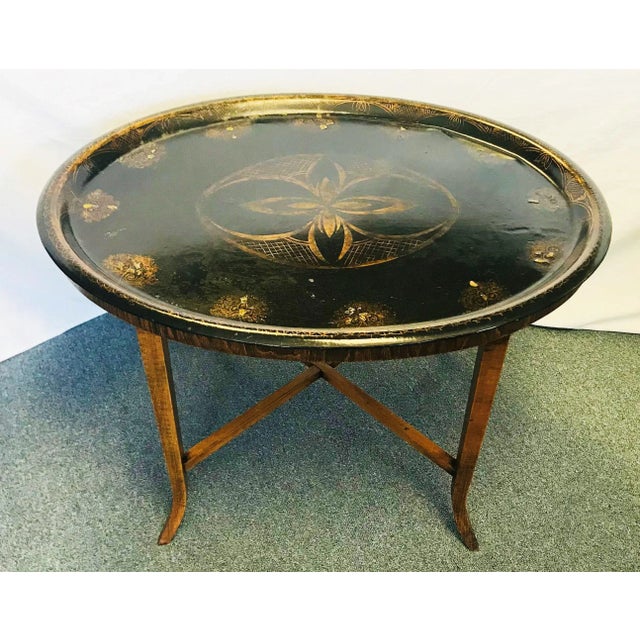 Very elegant! This 19th century painted tole tray sits atop a wooden base with fine saber legs. The top is made of metal...