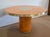 This round table, with its orange tones, is composed of a top and a large cylindrical base made of four-leaf cedar veneer....