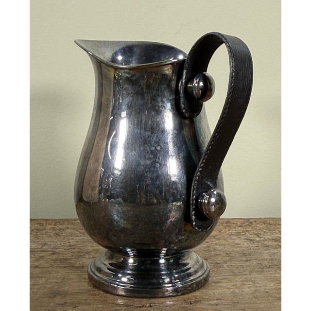 This silver plated water pitcher was made by Plata Lappas of Argentina. The piece features a traditional baluster form...