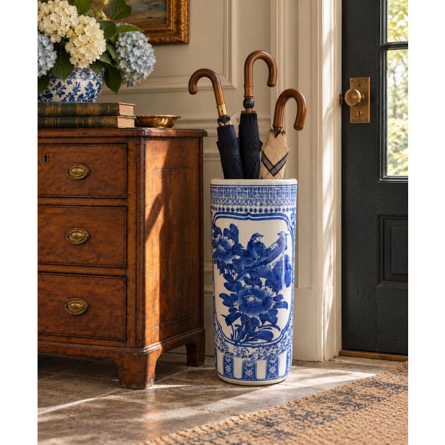 A classic blue and white porcelain umbrella stand in the chinoiserie tradition, featuring finely rendered birds among...