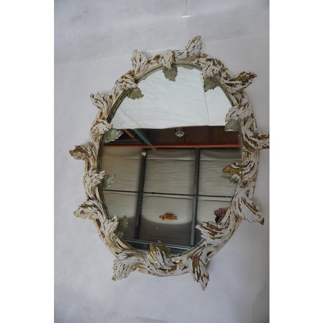 Italian oval-shaped mirror with leaves carved into the frame surrounding the mirror. Originally gilt wood, but it has worn...