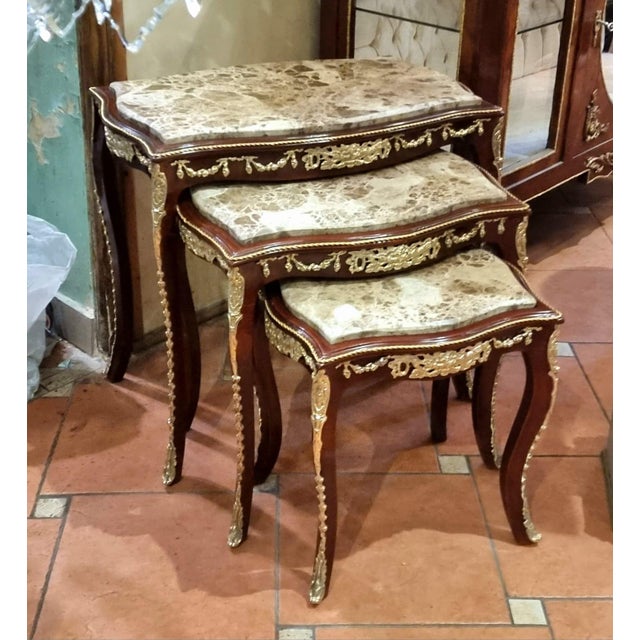 Elegant Rococo style nesting tables featuring a luxurious set of three accent tables topped with sophisticated beige and...
