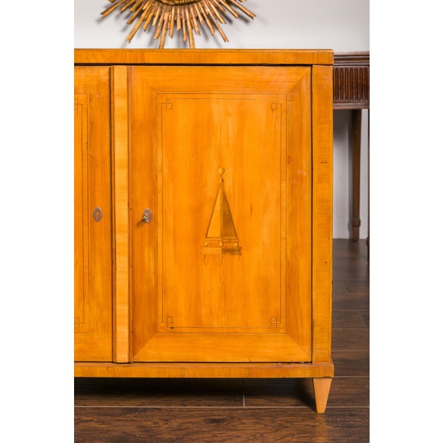 An Austrian Biedermeier period walnut buffet from the mid-19th century, with marquetry motifs and tapered feet. Created in...