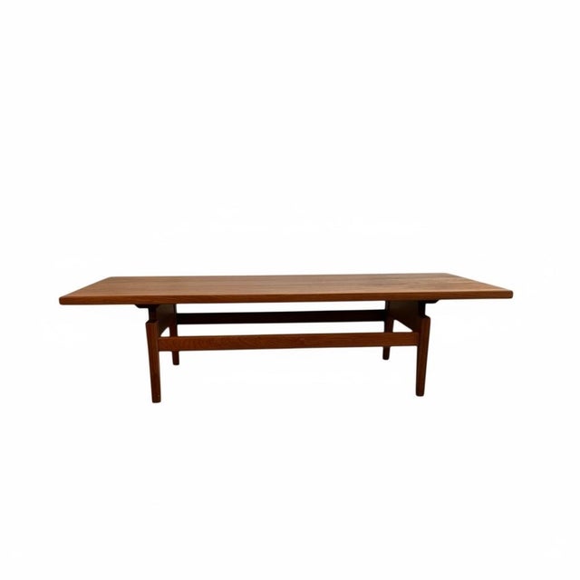 A classic mid-century modern teak coffee table by Jens Risom, showcasing the warm golden tones and expressive cathedral...